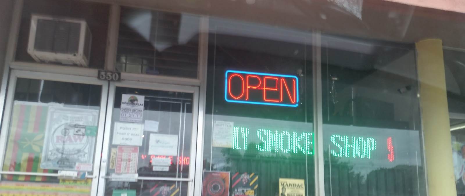 Hi Supply Smoke Shop's storefront at night, with the neon OPEN sign and SMOKE SHOP lights on